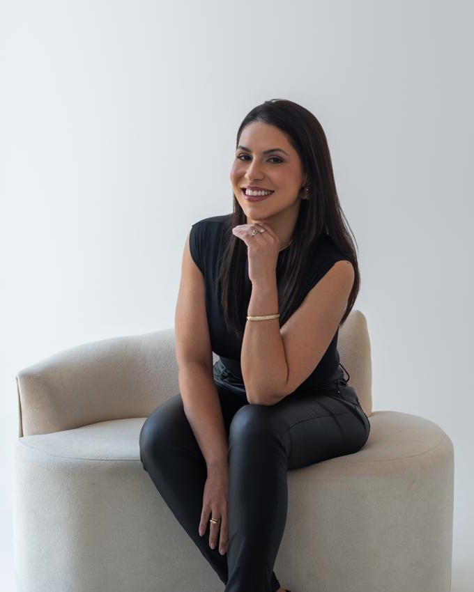 Luana Amaral, Biomédica Esteta, sorrindo sentada em uma poltrona clara